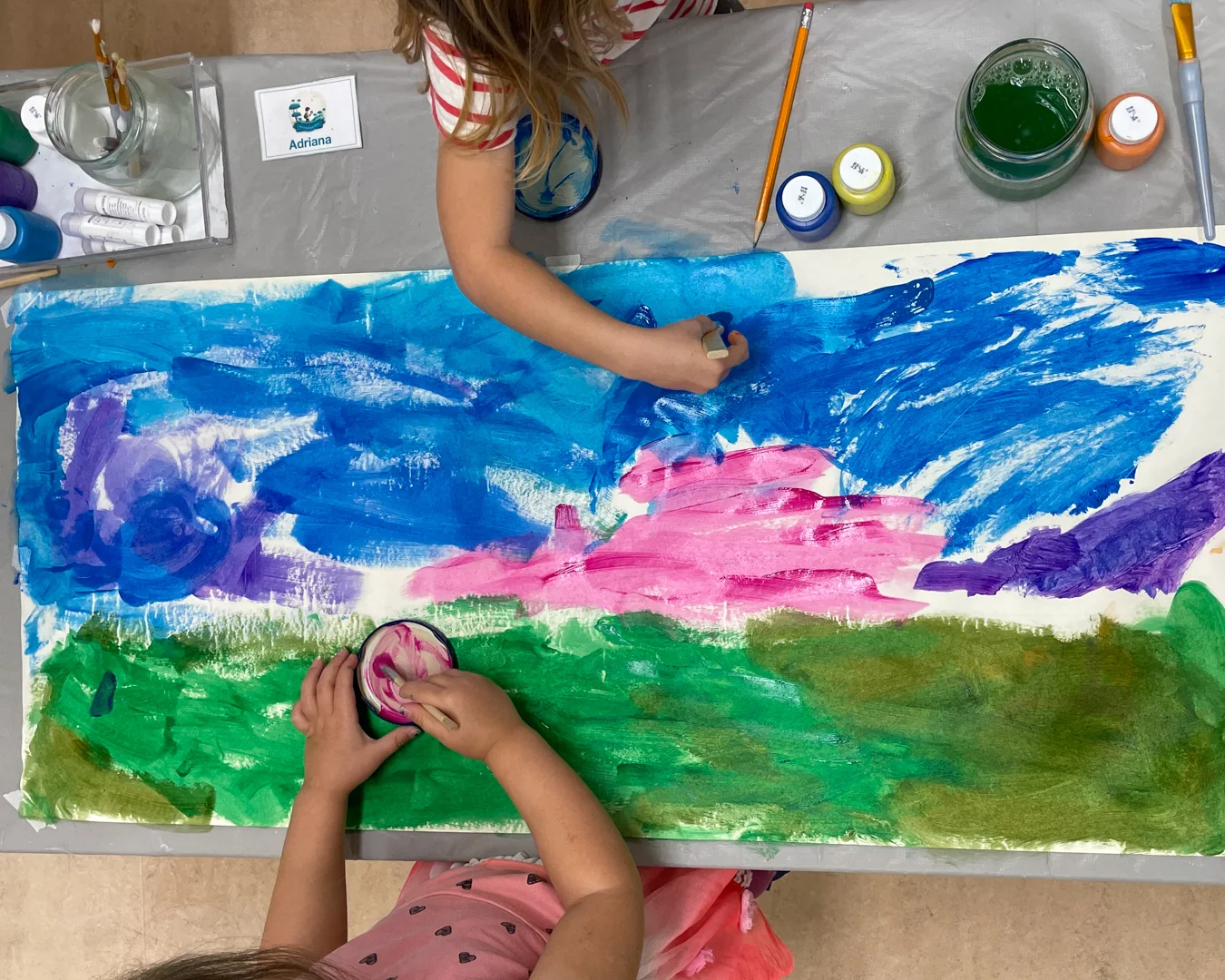 Preschool children painting together at a table, exploring colors and creativity. Preschool and After school Care in Cochrane AB